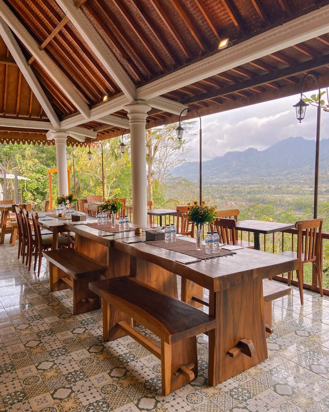 Covered dining room with wooden tables facing the Menoreh Hills at Kedai Bukit Rhema near Borobudur